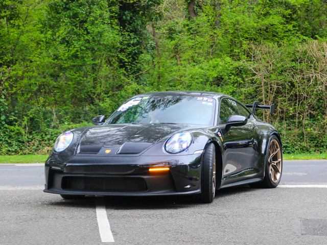 Une Porsche 911 GT3 noire sur un parking.