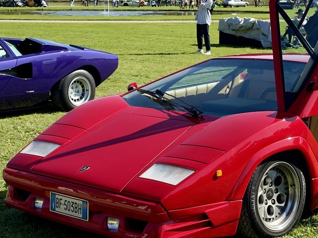 Une Lamborghini Countach rouge portes ouvertes sur la pelouse.