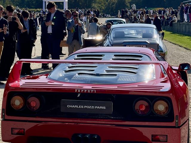 Une Ferrari F40 rouge entourée de visiteurs.