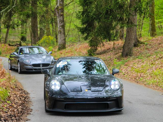 Une Porsche 911 noire sur une route de forêt.